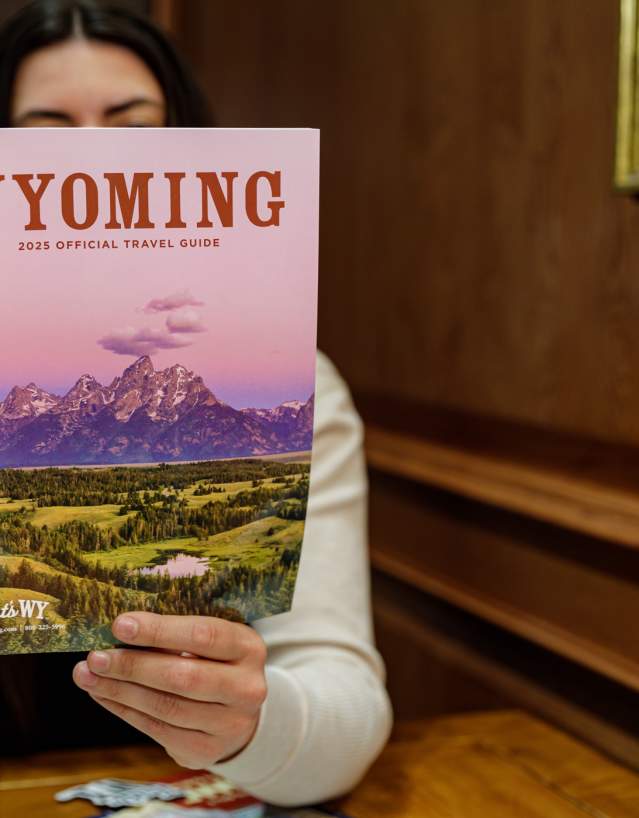 Person holding and reading the official printed Travel Guide