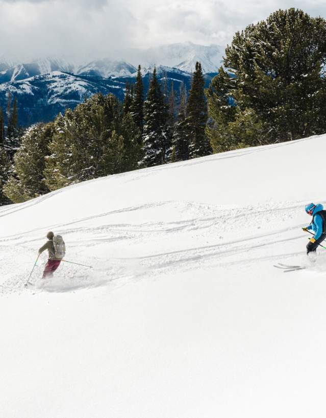 Three people backcountry skiing through snowy terrain in the Absaroka Mountains, Park County, Wyoming.