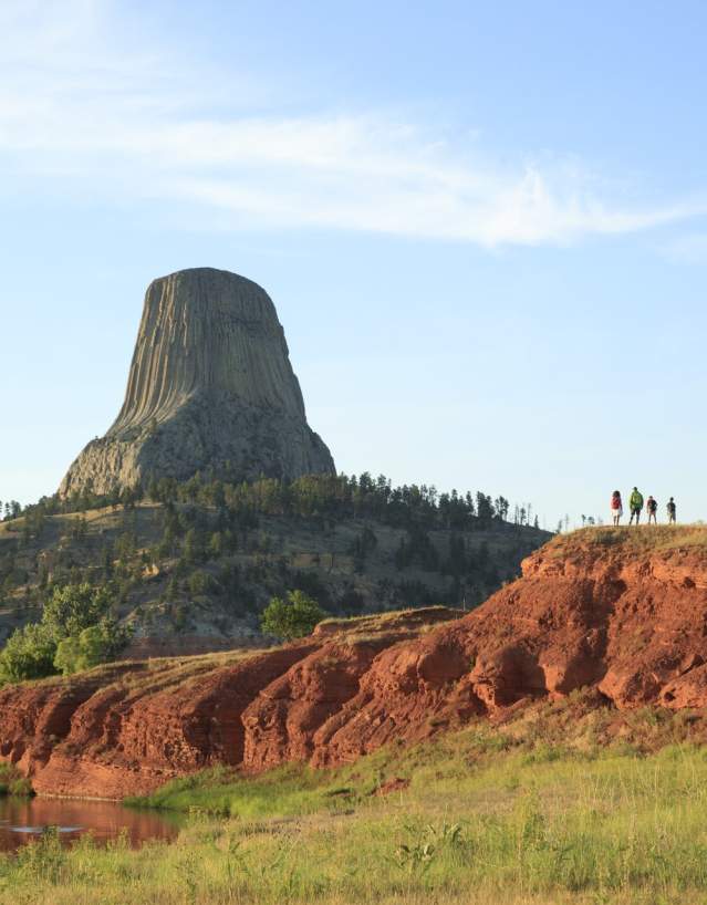 Hiker walking along a trail surrounded by lush greenery in Wyoming at sunrise