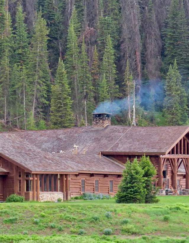 Lodge with smoke rising from fireplace in forest.