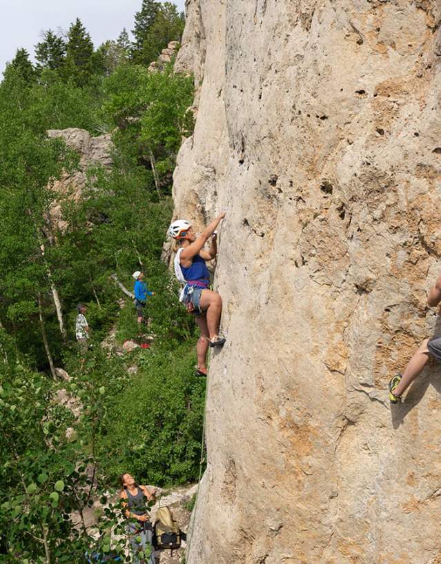 Rock climbers scaling a mountainside in the forest.