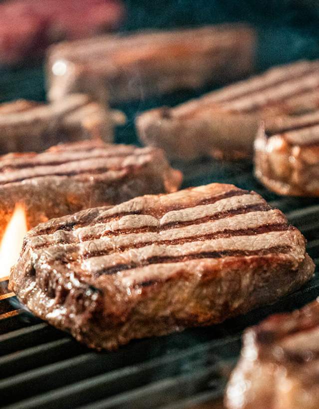 Beef steaks on a fiery grill.