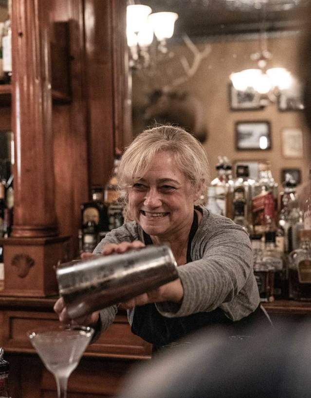 Bar worker with a smile pouring a drink in a glass.