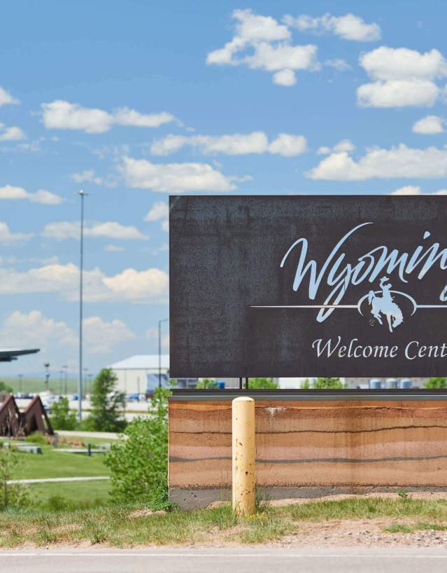 Bronze Wyoming welcome center sign set against clear blue sky.
