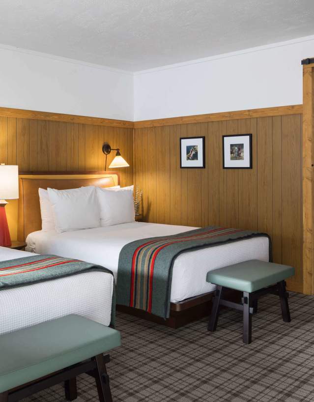 Hotel room with two made beds and open doorway to en suite bathroom.