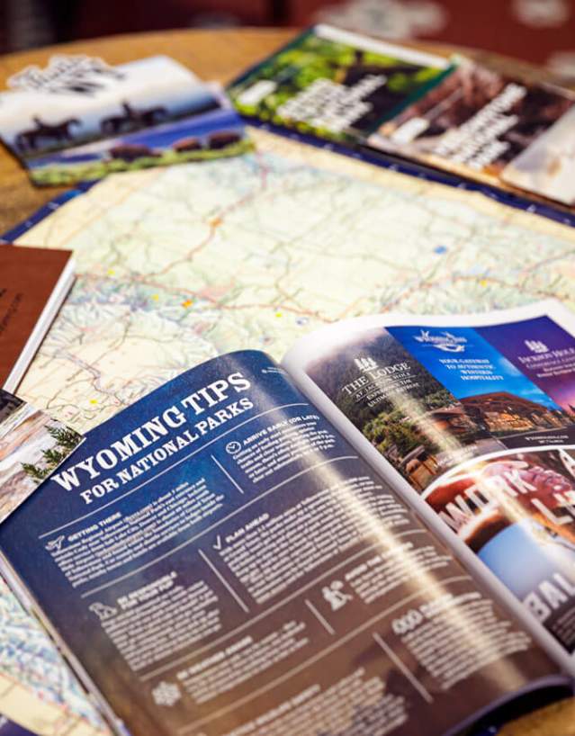 The official Wyoming Travel Guide flipped open showing pages inside the printed magazine.