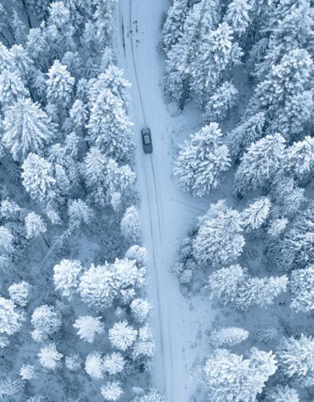 Aerial view of car driving downm a snowy road in Wyoming winter.