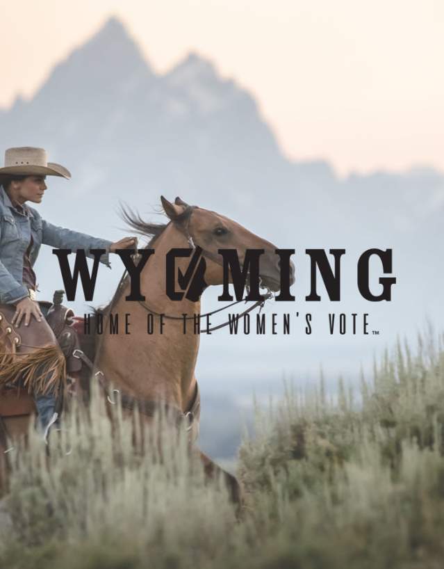 Woman riding her horse up a hill with the Grand Tetons in the background.