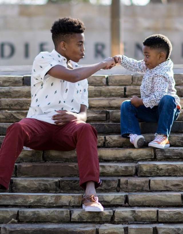 One big kid and one little kid fist bumping sitting on steps