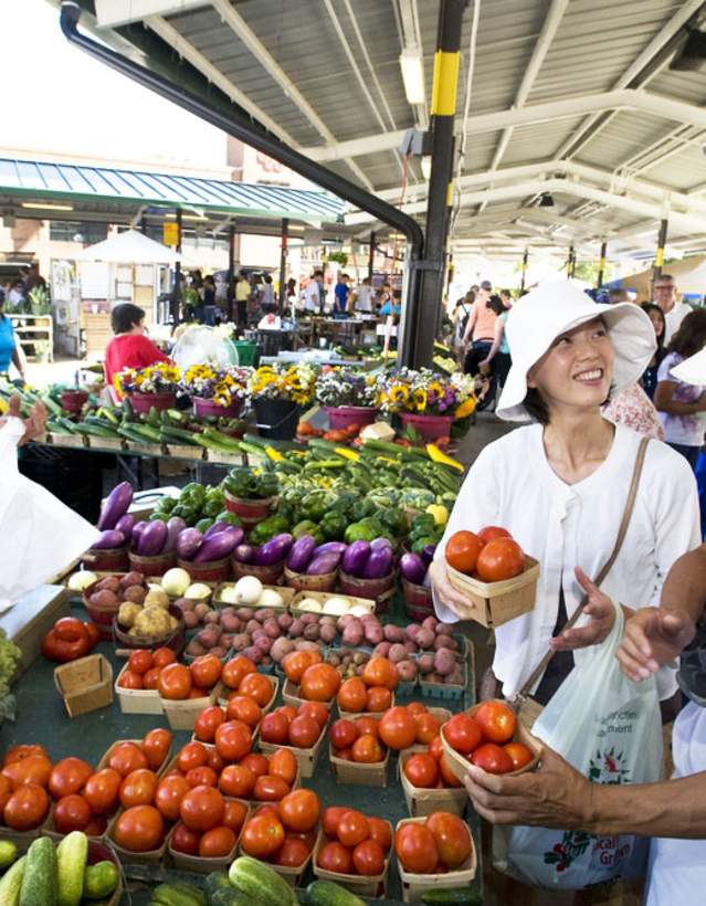 Family buying produce from a woman st the Ann Arbor Farmers Market