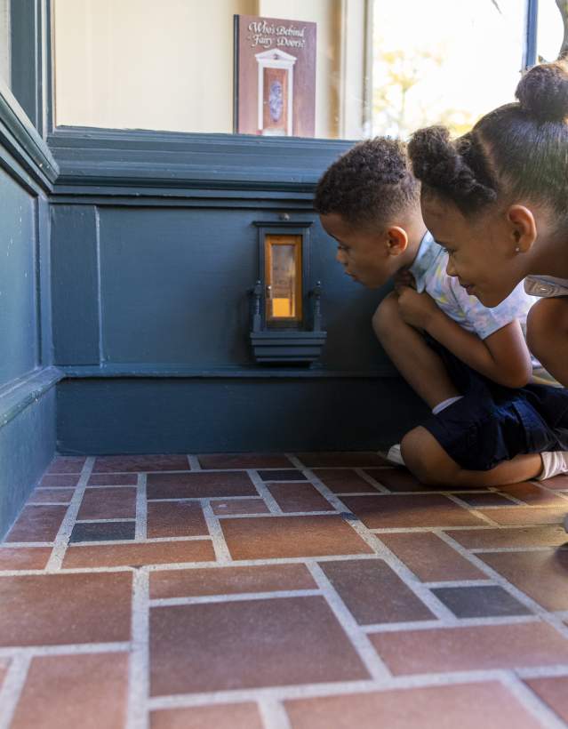 Two children kneeling down to look in a fairy door