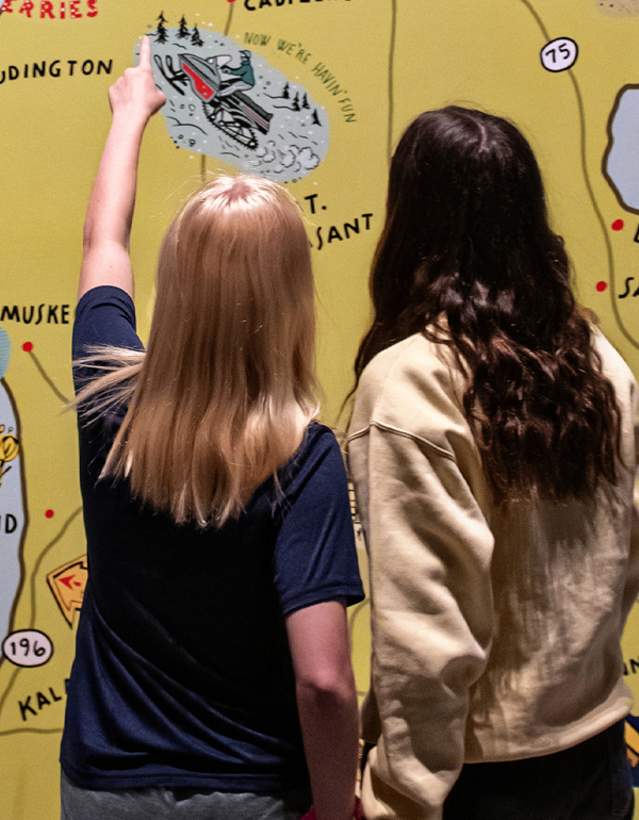Two girls looking at mural of michigan map
