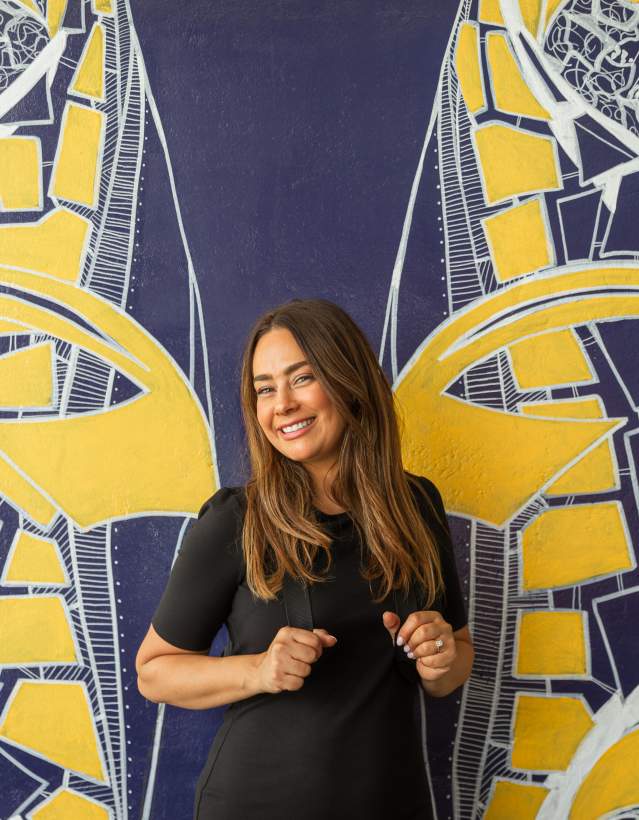 Woman smiling in front of U-M Wings Mural