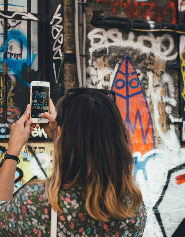 Woman taking photo of graffiti on cellphone