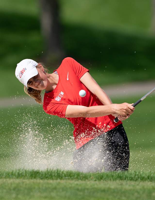 Female golfer hitting golf ball out of the sand trap