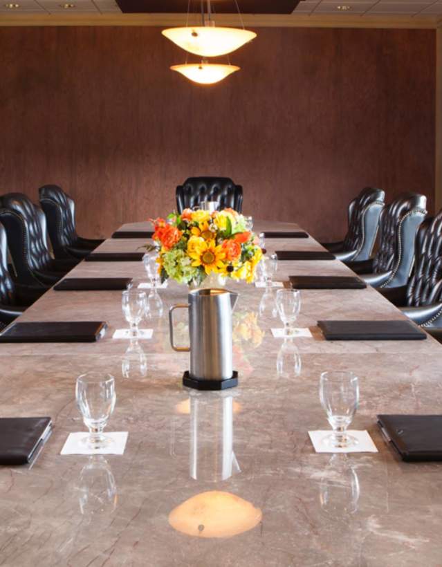 Boardroom table with black chairs and flower arrangement