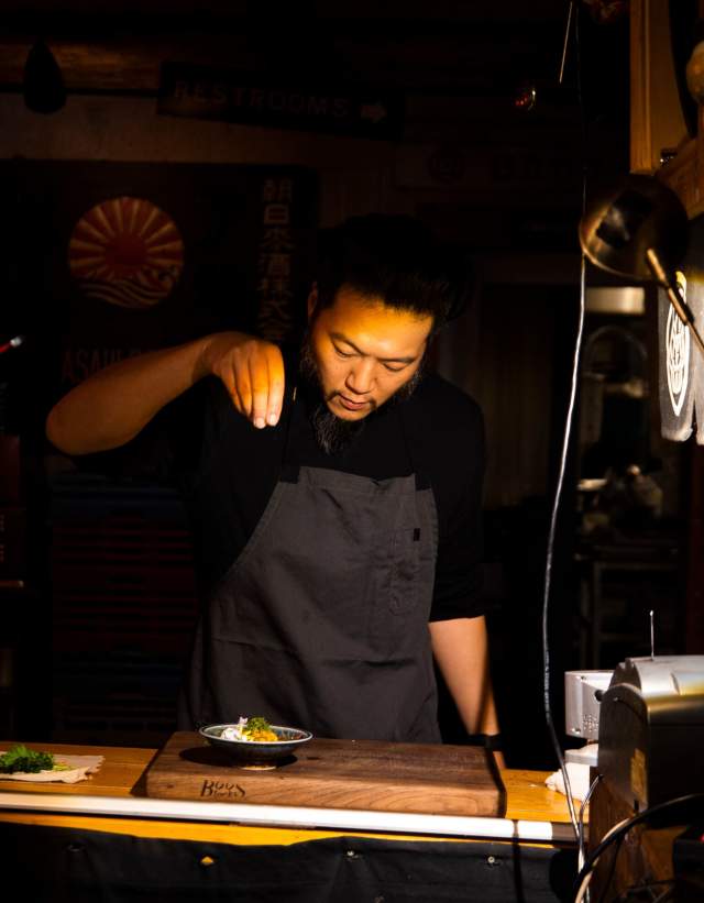 Chef Tatsu Aikawa sprinkles ingredients over a dish