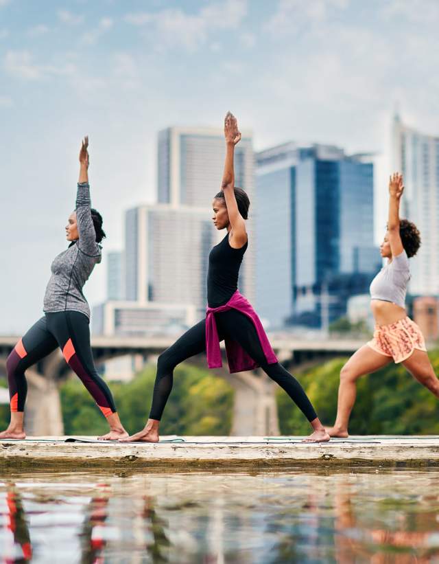 Three women practicing yoga on dock at Lady Bird Lake in Austin Texas