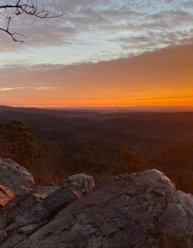 The sun rises over a rocky overlook called Kings Chair at Oak Mountain State Park.