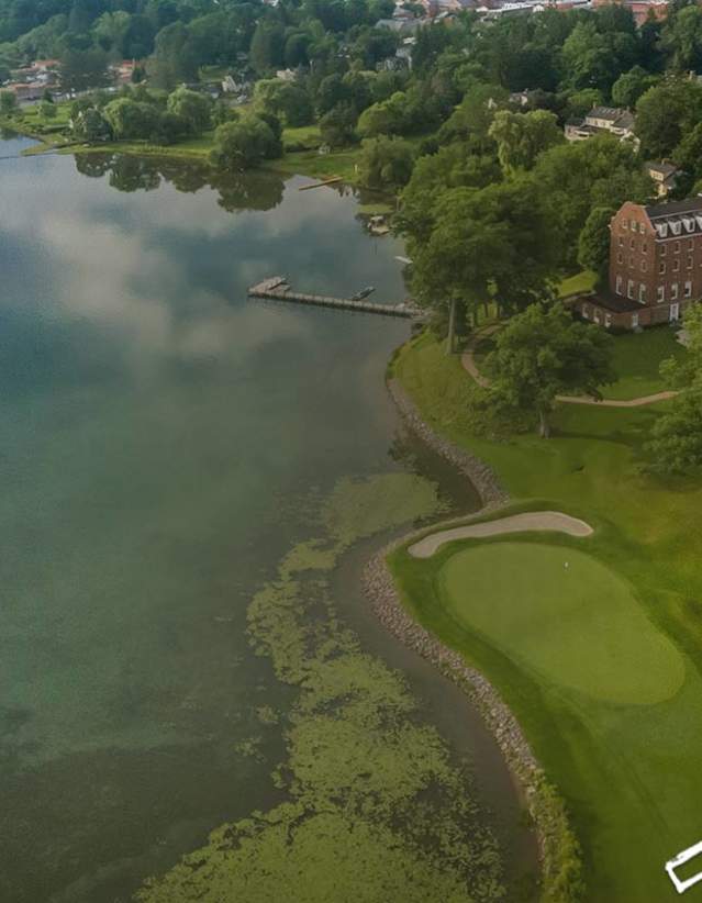 An aerial of a golf course and hotel with a lake to the left.