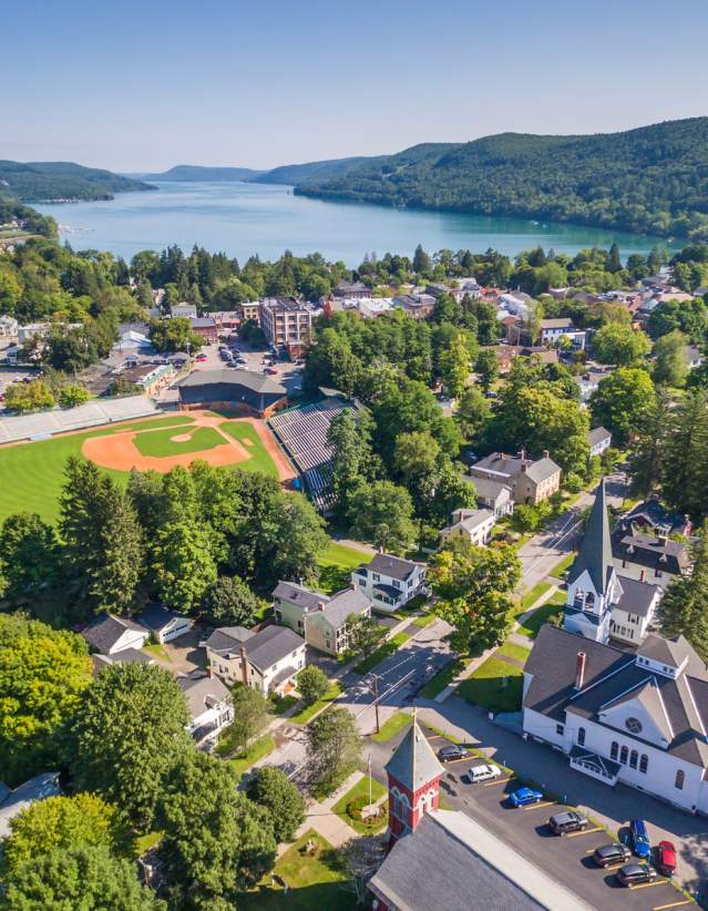An aerial photo of then Village of Cooperstown during summer with a baseball field and lake.