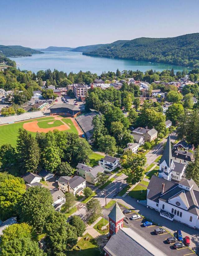 An aerial photo of Cooperstown during summer with a baseball field and the lake.