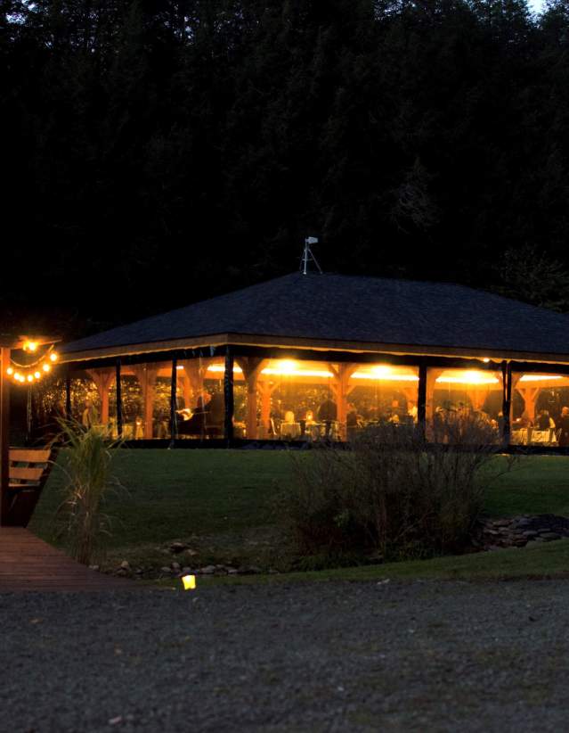 A lit pavilion at dusk with a lightly lit pathway in the foreground.