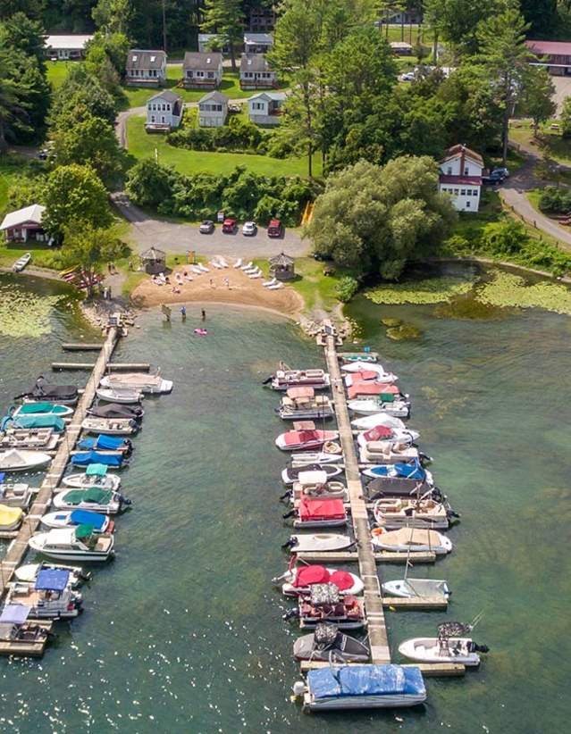 An aerial photo of a dock with a variety of boats docked during summer.