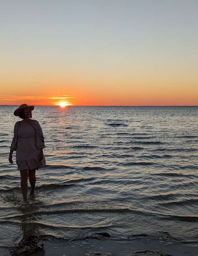A woman walks in the shallow waters of St. Joseph Bay at Sunset