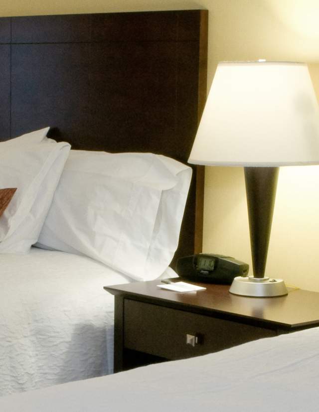 Man reading the newspaper in his Hotel Room with two beds and two lamps