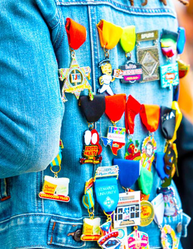 Back of person wearing jean jacket filled with Fiesta medals.