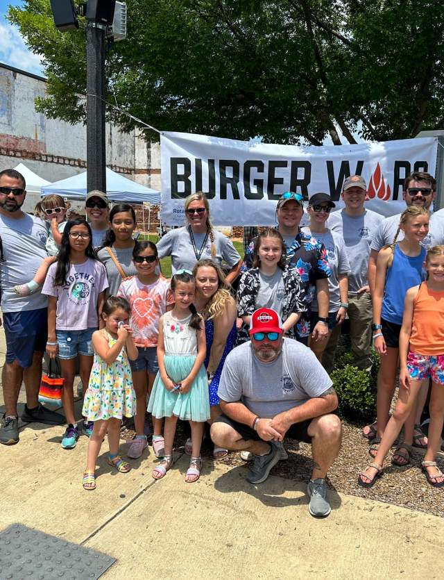 group of attendees in front of the burger war banner