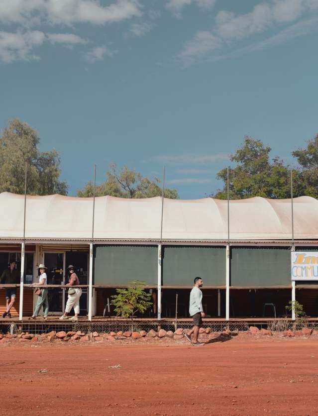 Fuel bowser and community store at Imintji Community on the Gibb River Road. Two people are walking along the small store verandah, while one walks outside