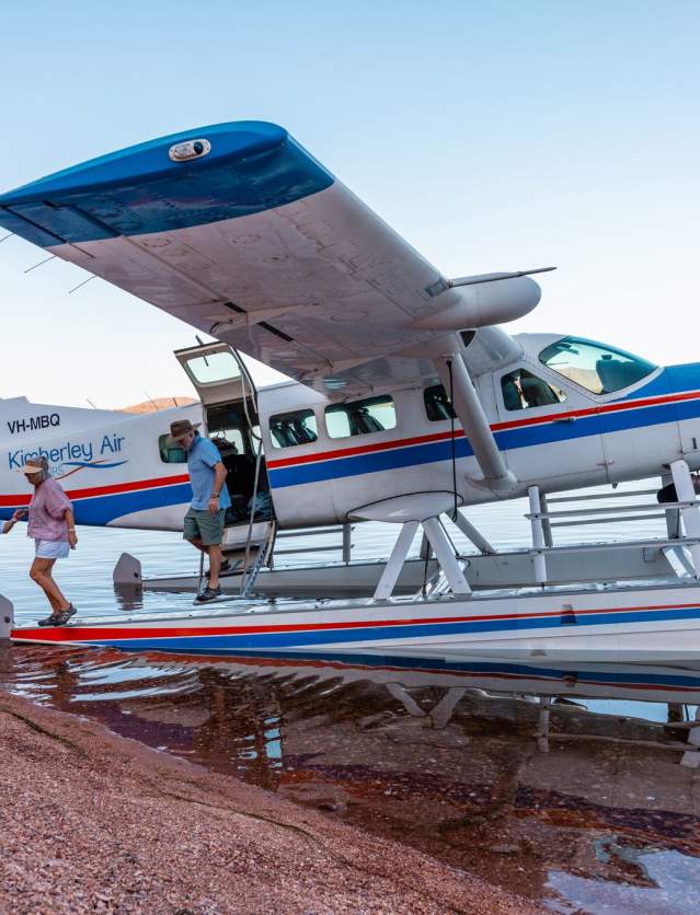 Pilot helps passengers alight from the seaplane which has landed alongside a remote island in Lake Arygle, the Kimberley, Western Australia