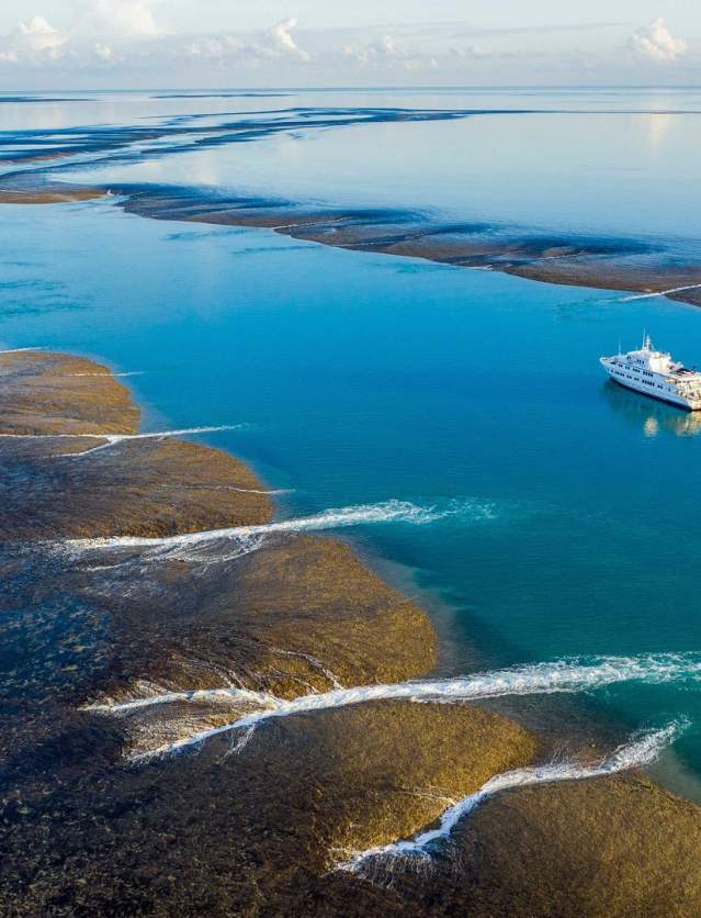 Aerial shot of the True North cruise ship at Montgomery Reef on the Kimberley Coast with the tide starting to recede from the reef