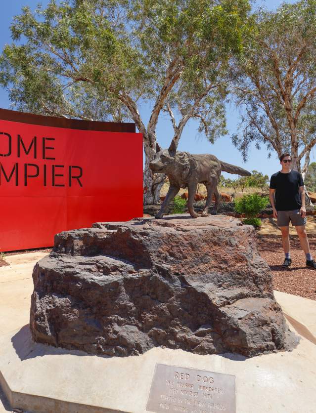 People standing alongside the statue of Red Dog outside Dampier in the Pilbara. This marks the start of the Red Dog Walking Trail
