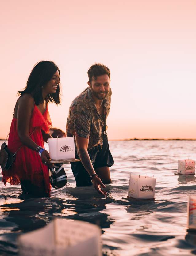 A couple wading into the ocean at Gantheaume Point, Broome to place their floating lanterns into the ocean at sunset.