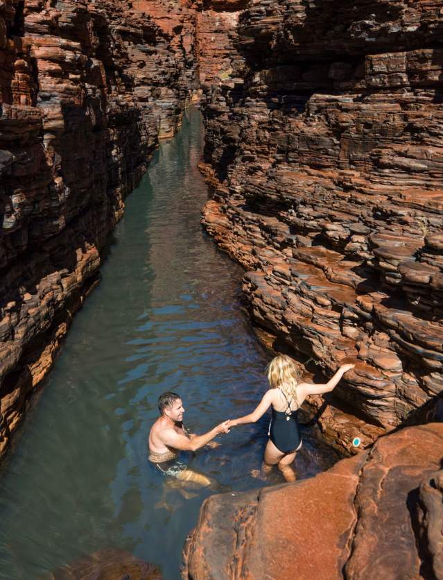 A father and daughter navigate the Spiderwalk in Hancock Gorge by descending into the water through the centre of this narrow gorge.