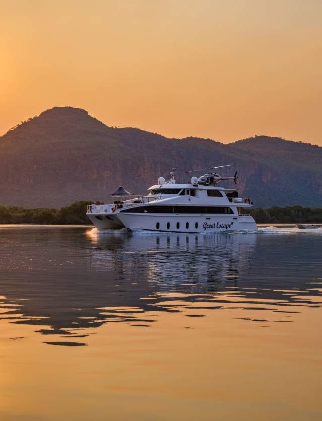 An expedition cruise vessel on the Kimberley Coast at sunset, with a helicopter on board