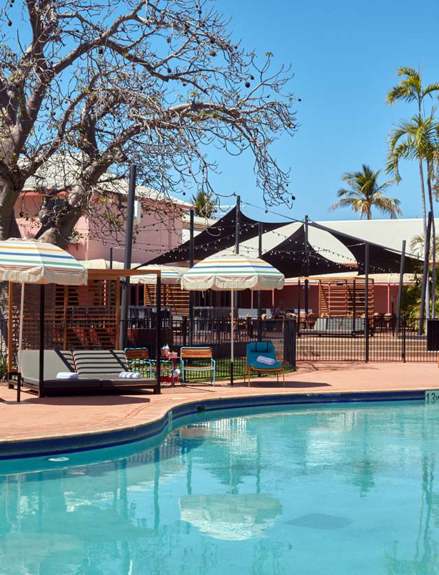 A view of the resort pool area at the Continental Hotel in Broome - loungers and sun shades line the edge of the pool, and the hotel is visible in the background
