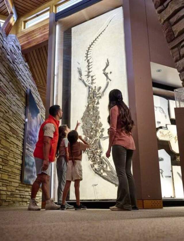 A family looks up at the Fossil Butte National Monument, as a young girl points in amazement at the fossil exhibit before them. 