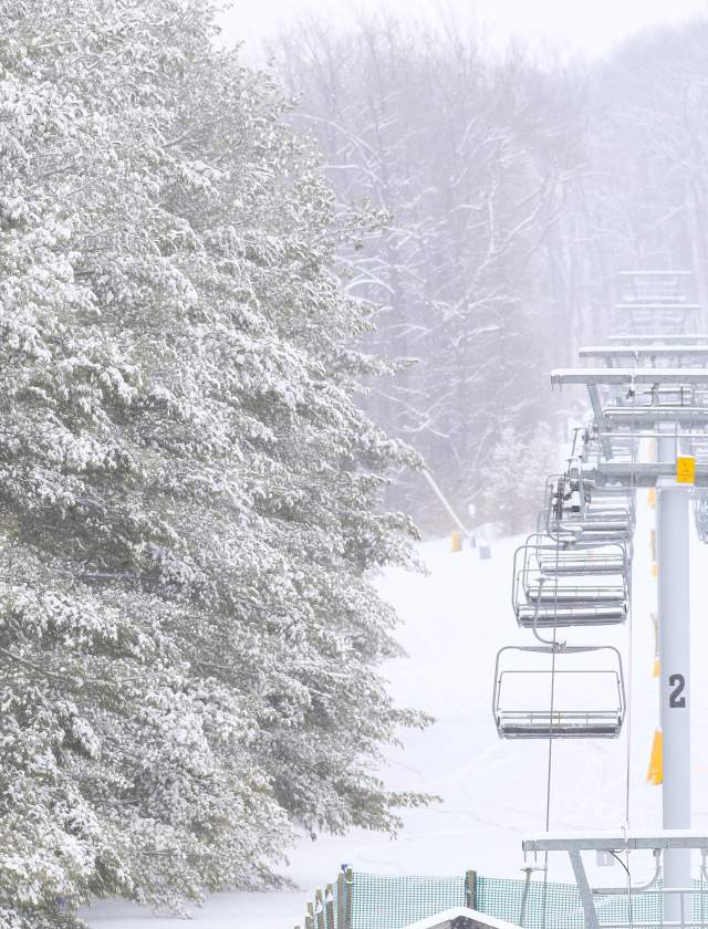 Aerial of a people on ski lifts with snow falling down