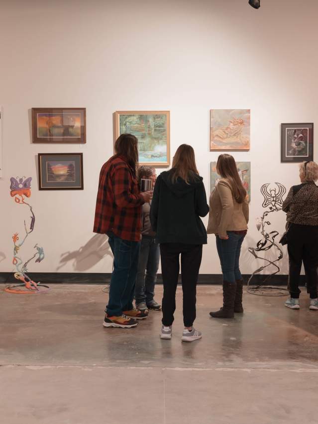 Visitors enjoying diverse artworks at Amarillo's First Friday Art Walk, featuring paintings, sculptures, and other creative pieces in a gallery setting.