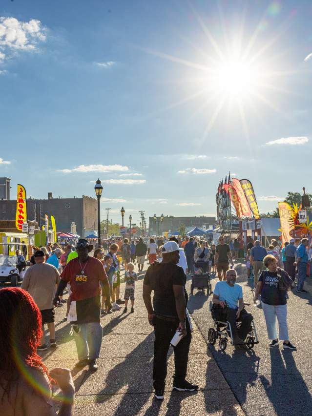 The sun shines over a crowd of people walking through downtown Paducah's annual BBQ on the River event.