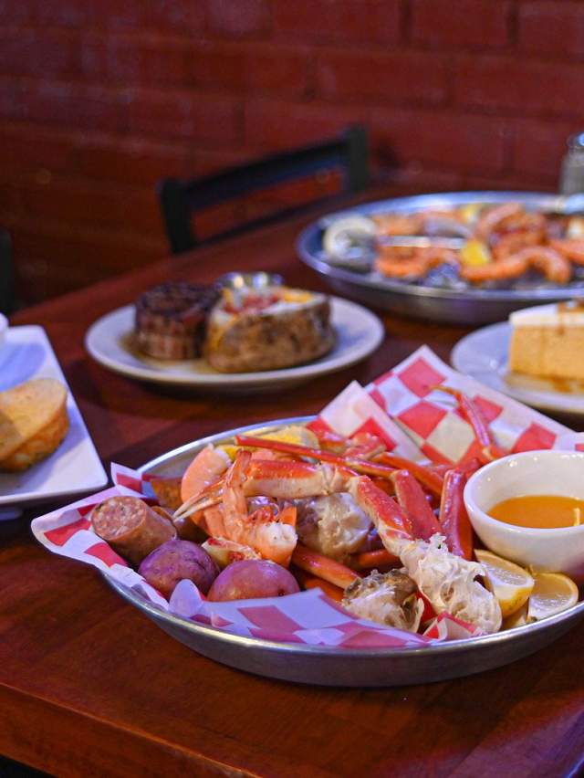 A table covered with crab legs, steak, pie and more from AJs Oyster House in Fort Smith.