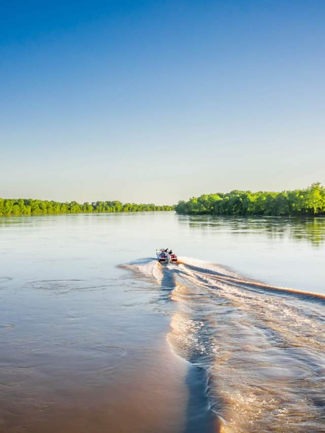 Water ripples behind a motor boat speeding across the Arkansas River.