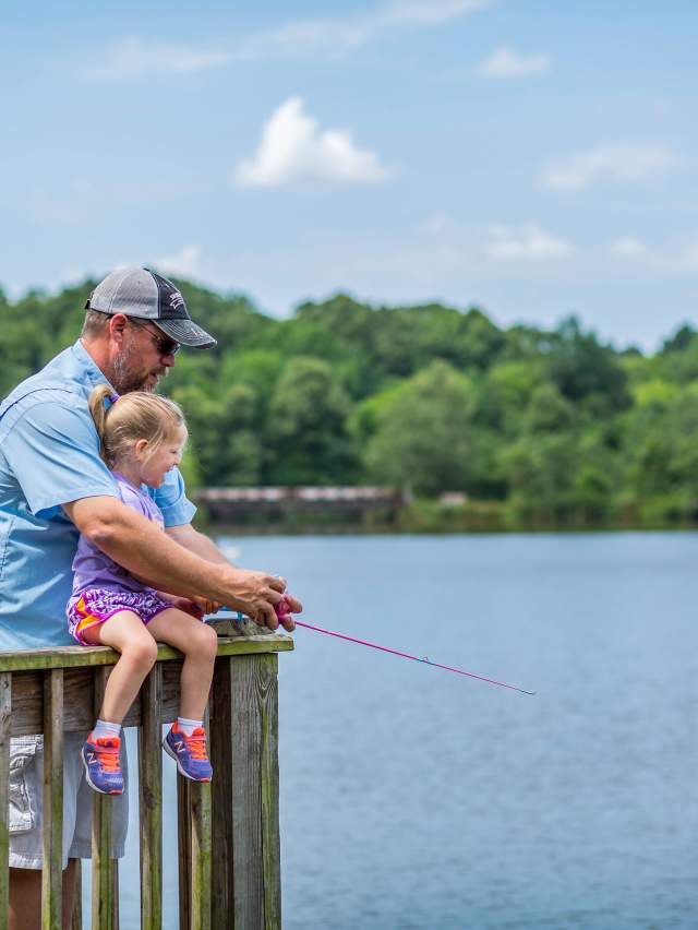 A dad teaches his young daughter to fish at Wells Lake in Fort Smith.