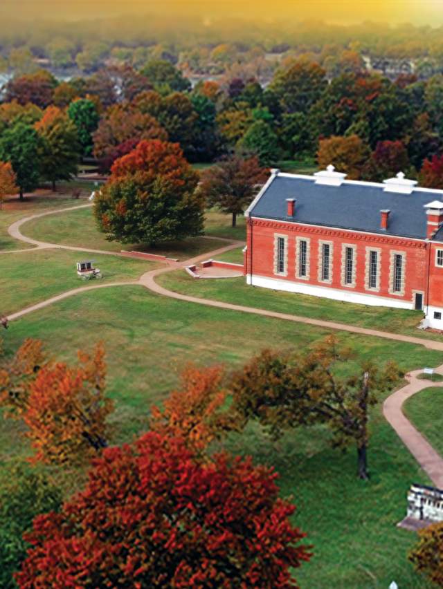 The Fort Smith National Historic site is surrounded by fall foliage with the Arkansas River in the backdrop.