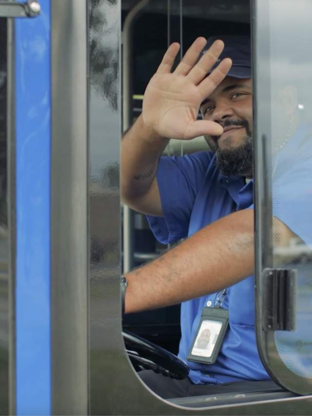 A bus driver waves as he drives a Fort Smith bus.