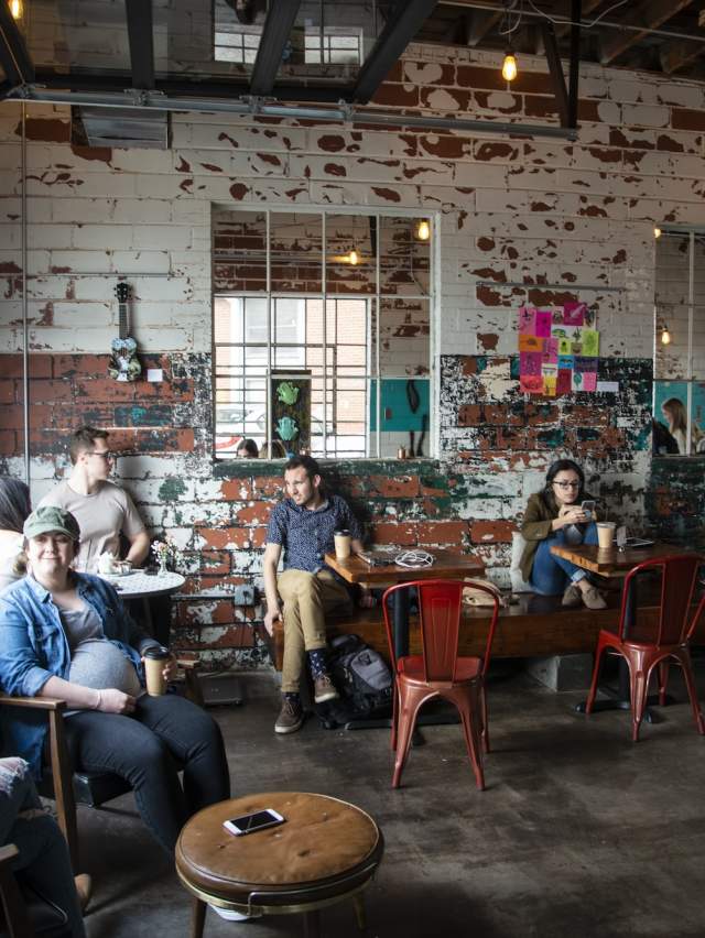 People sit in Fort Smith Coffee Company, drinking coffee, working, and chatting.